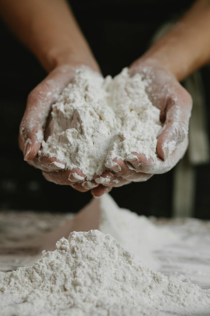 Close-up of a person holding a mound of flour in their hands inside a kitchen.